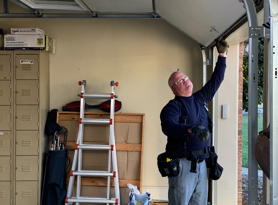 Garage door technician inspecting overhead track and hardware