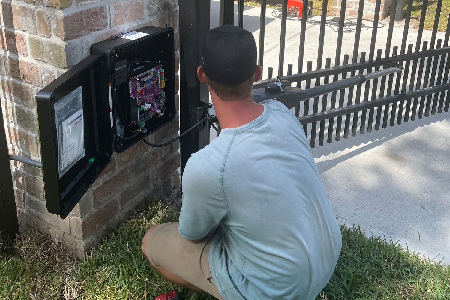 Automatic gate opener repair technician servicing control panel in Tarrant County